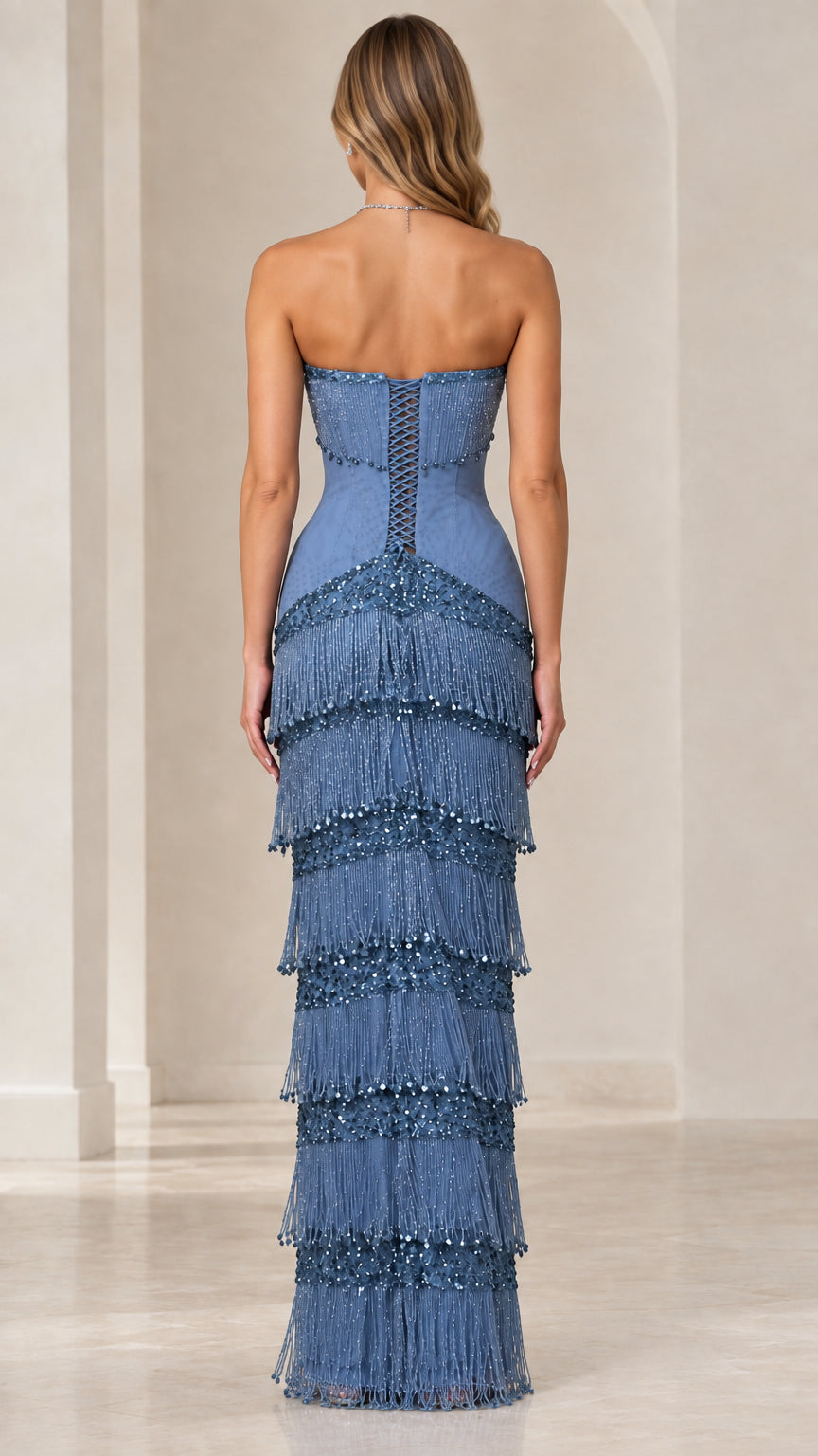 Back view of dusty blue evening gown showing lace-up corset detail and tiered fringe skirt