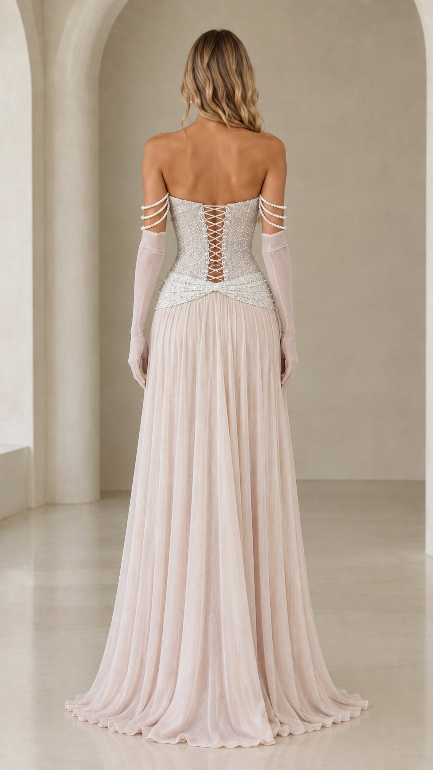 Back view of champagne formal gown highlighting the lace-up corset back and flowing skirt