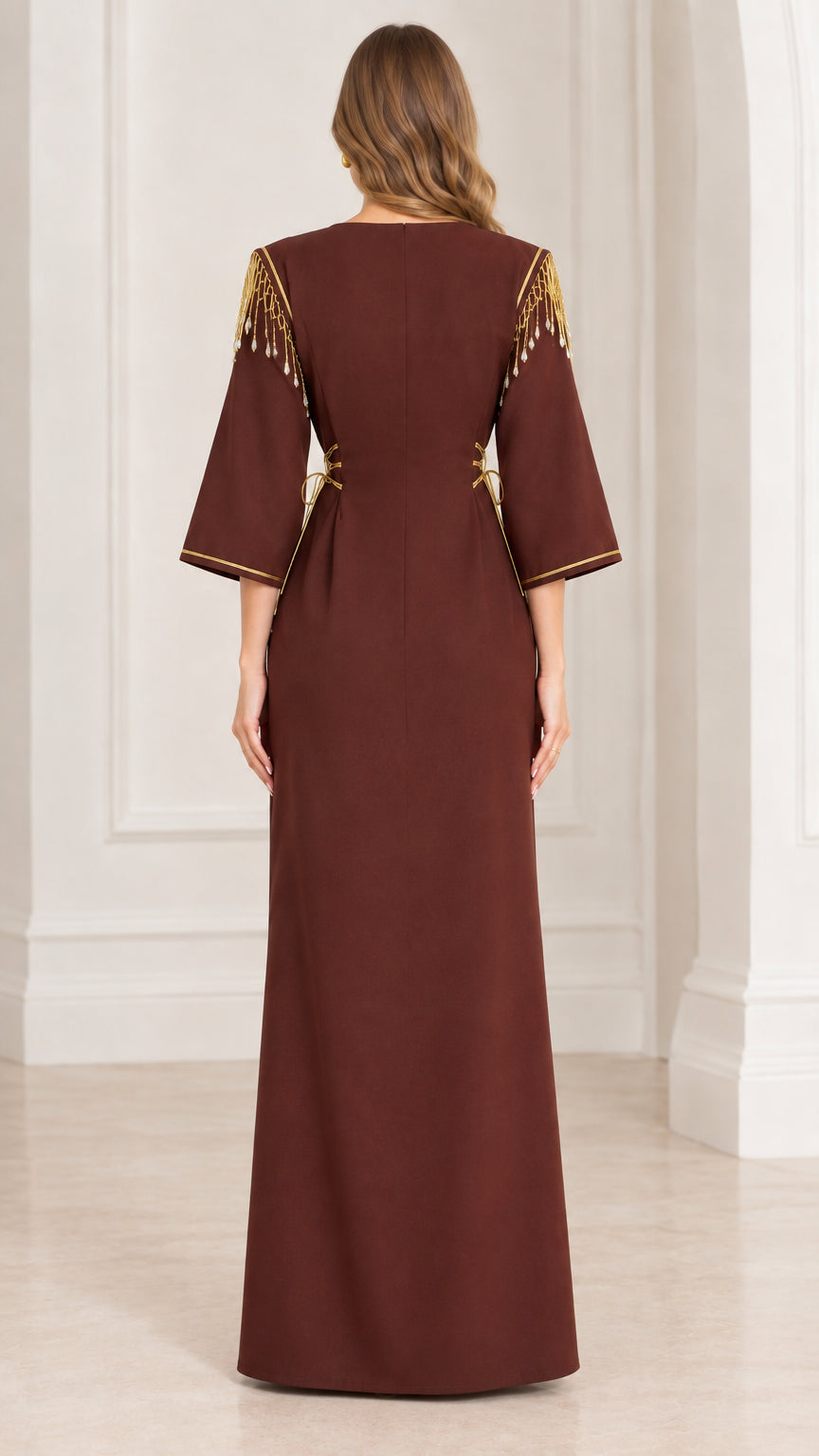 Back view of woman wearing brown floor-length formal gown with gold shoulder fringe