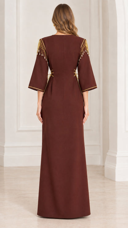 Back view of woman wearing brown floor-length formal gown with gold shoulder fringe