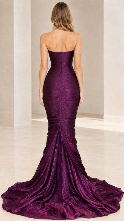 Back view of model in purple strapless fitted mermaid gown with flared train