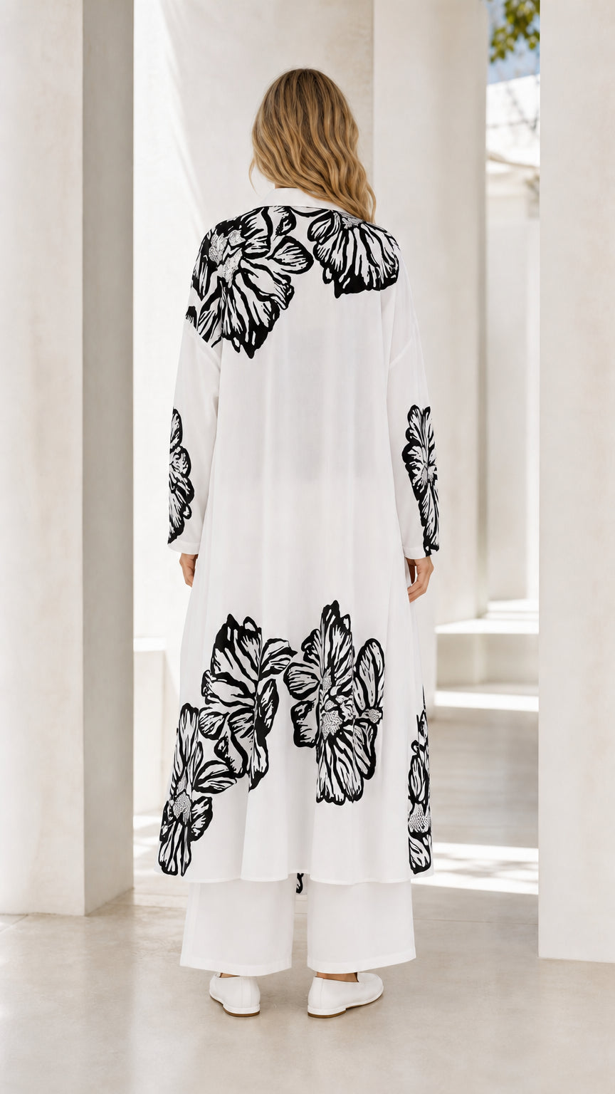 Back full view of women's white floral print longline shirt and wide-leg trousers