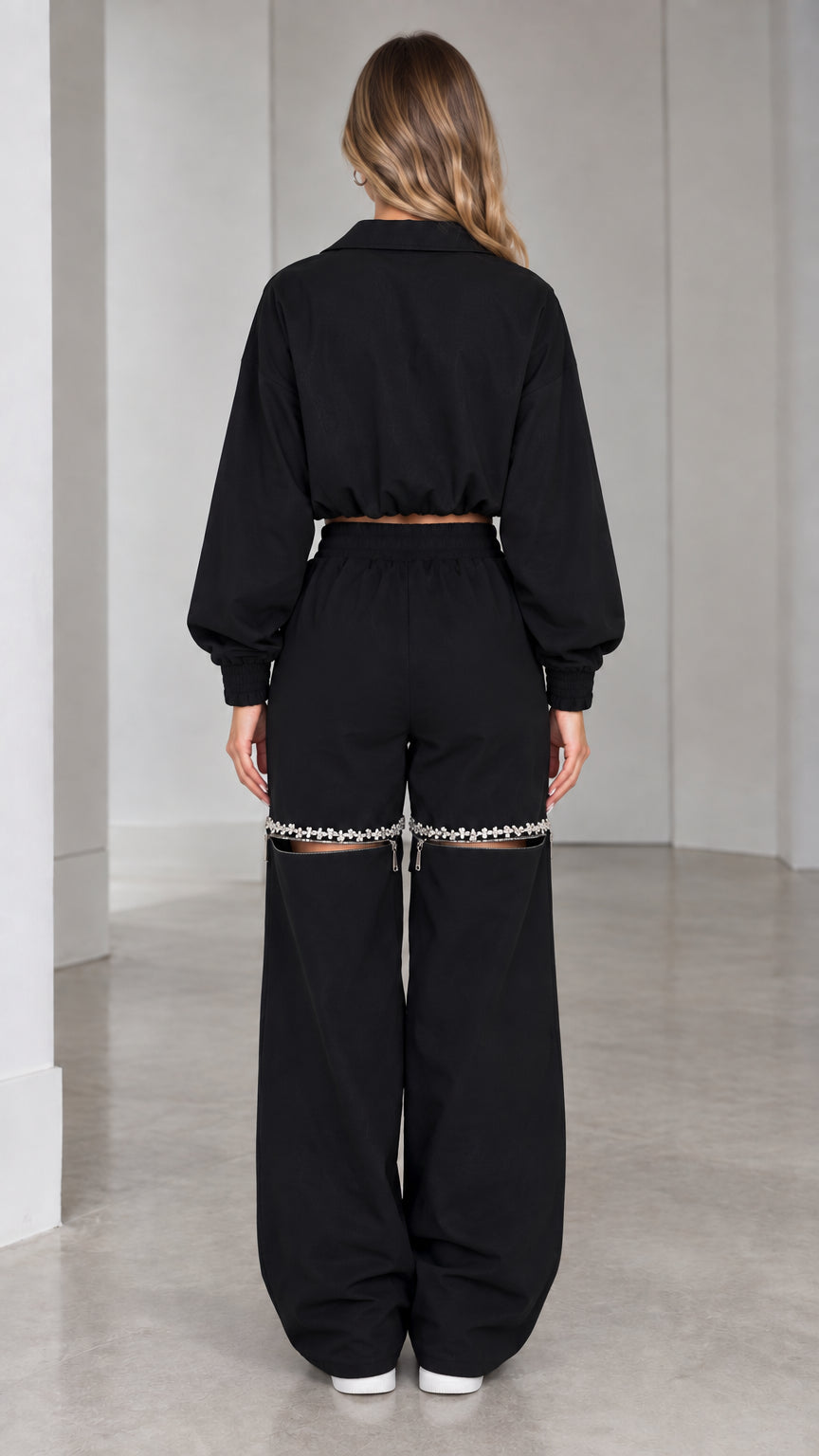 Back view of model wearing black cropped track jacket and wide-leg pants
