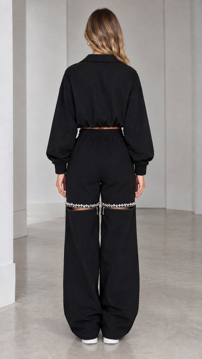 Back view of model wearing black cropped track jacket and wide-leg pants