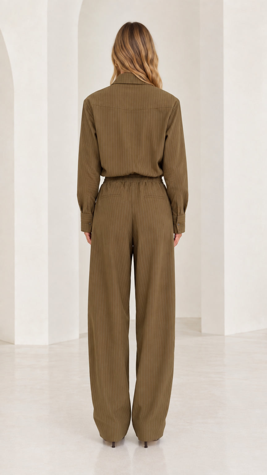 Back full-length view of woman in olive green long sleeve elastic waist jumpsuit