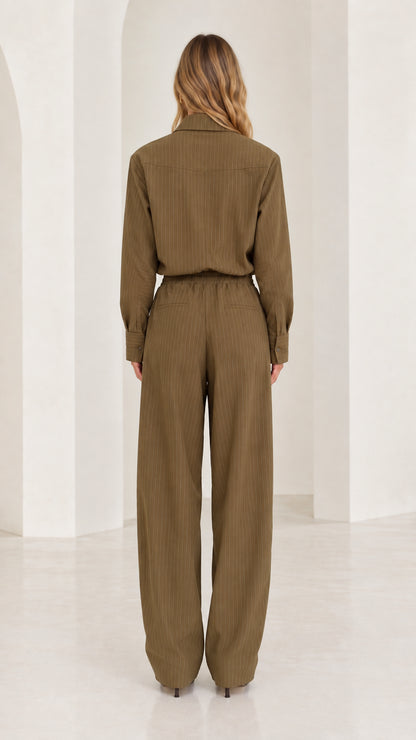 Back full-length view of woman in olive green long sleeve elastic waist jumpsuit