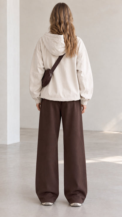 Back view of model wearing beige lightweight hooded pullover jacket