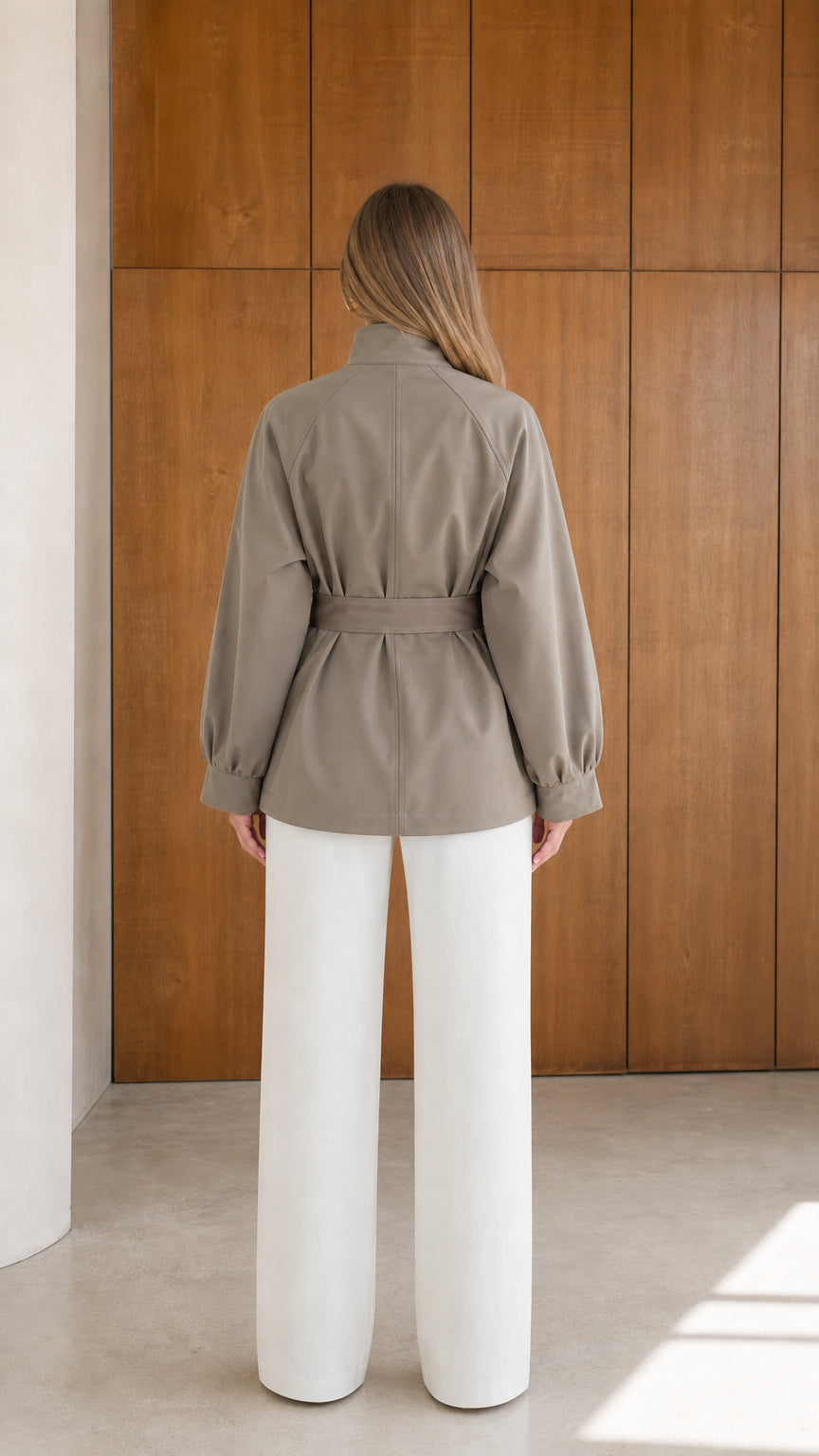 Back view of model wearing taupe belted short trench coat showing clean seam construction