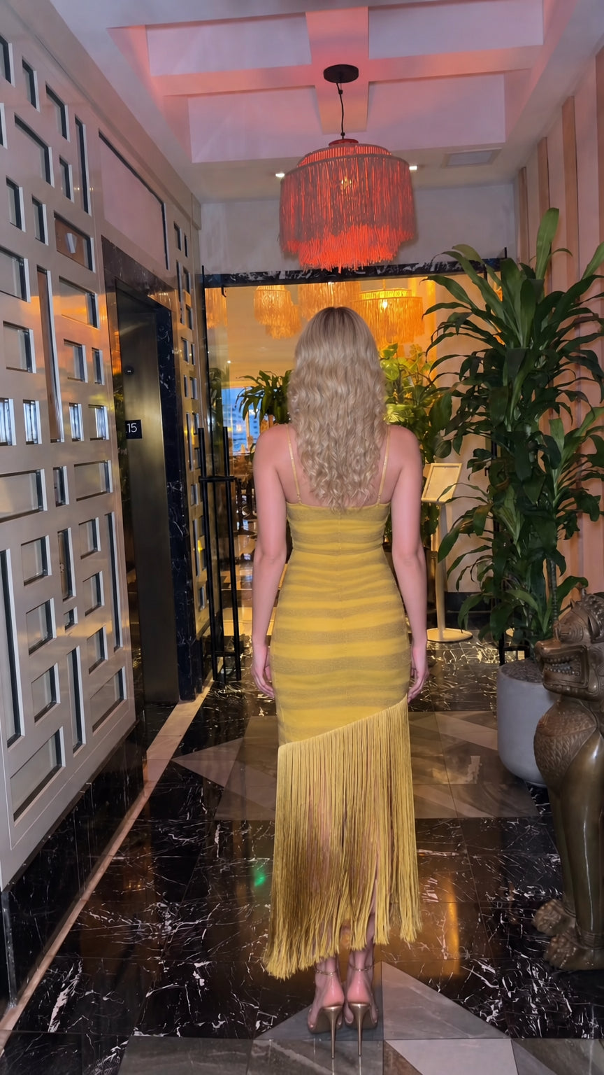 Back view of woman wearing Mustard Yellow ruched cocktail dress with fringe detail