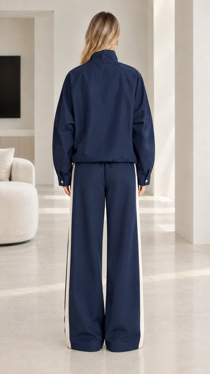 Back view of woman wearing navy blue colorblock tracksuit jacket and wide leg pants