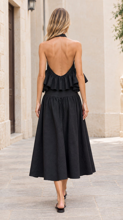 Back view of model showcasing the open back halter ruffle top and black midi skirt