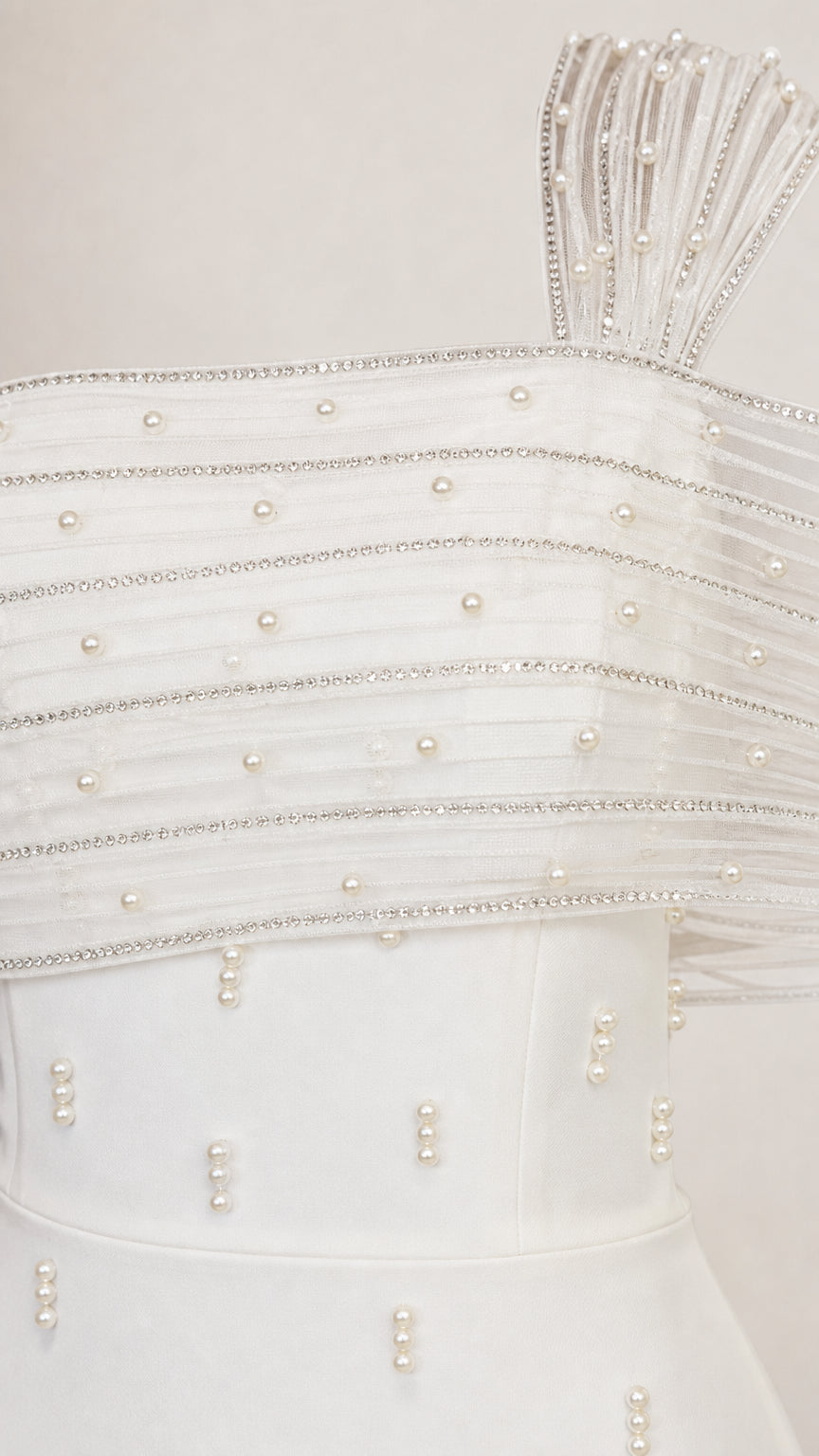 Close-up detail of pearl and rhinestone embellishments on sheer pleated shoulder overlay