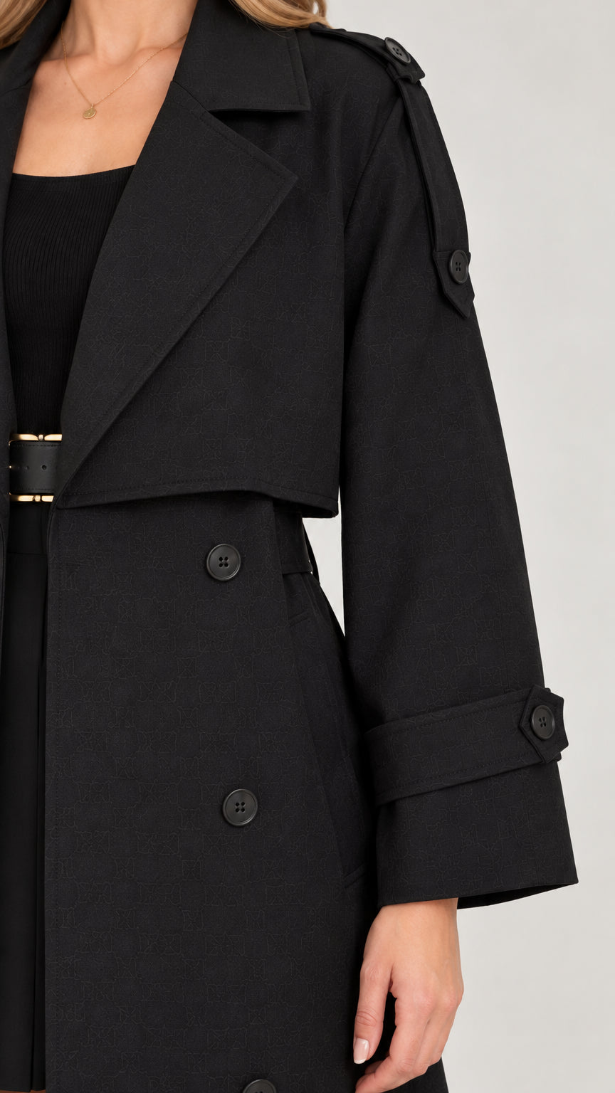 Close-up detail of wide lapel and shoulder tabs on black trench coat