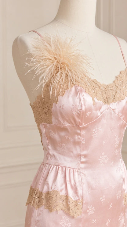Close-up detail of bodice showing blush pink satin jacquard, lace insets, and feather shoulder trim