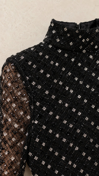 Close-up detail of black high mock neck and geometric sequin embellishment on mesh fabric