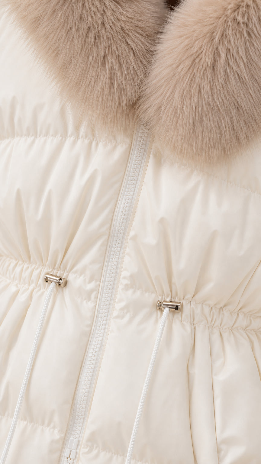 Close-up detail of cream puffer fabric, zipper closure, metal toggle drawstring, and faux-fur collar