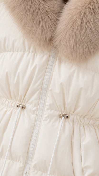 Close-up detail of cream puffer fabric, zipper closure, metal toggle drawstring, and faux-fur collar