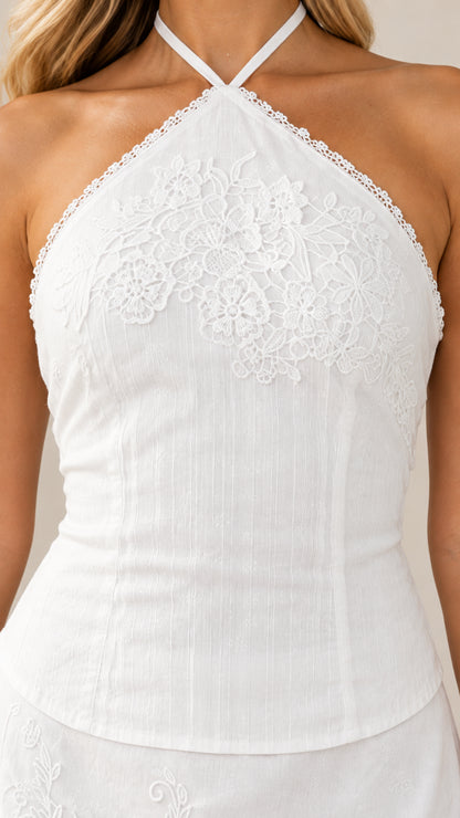 Close-up detail of floral lace embroidery on white halter bodice