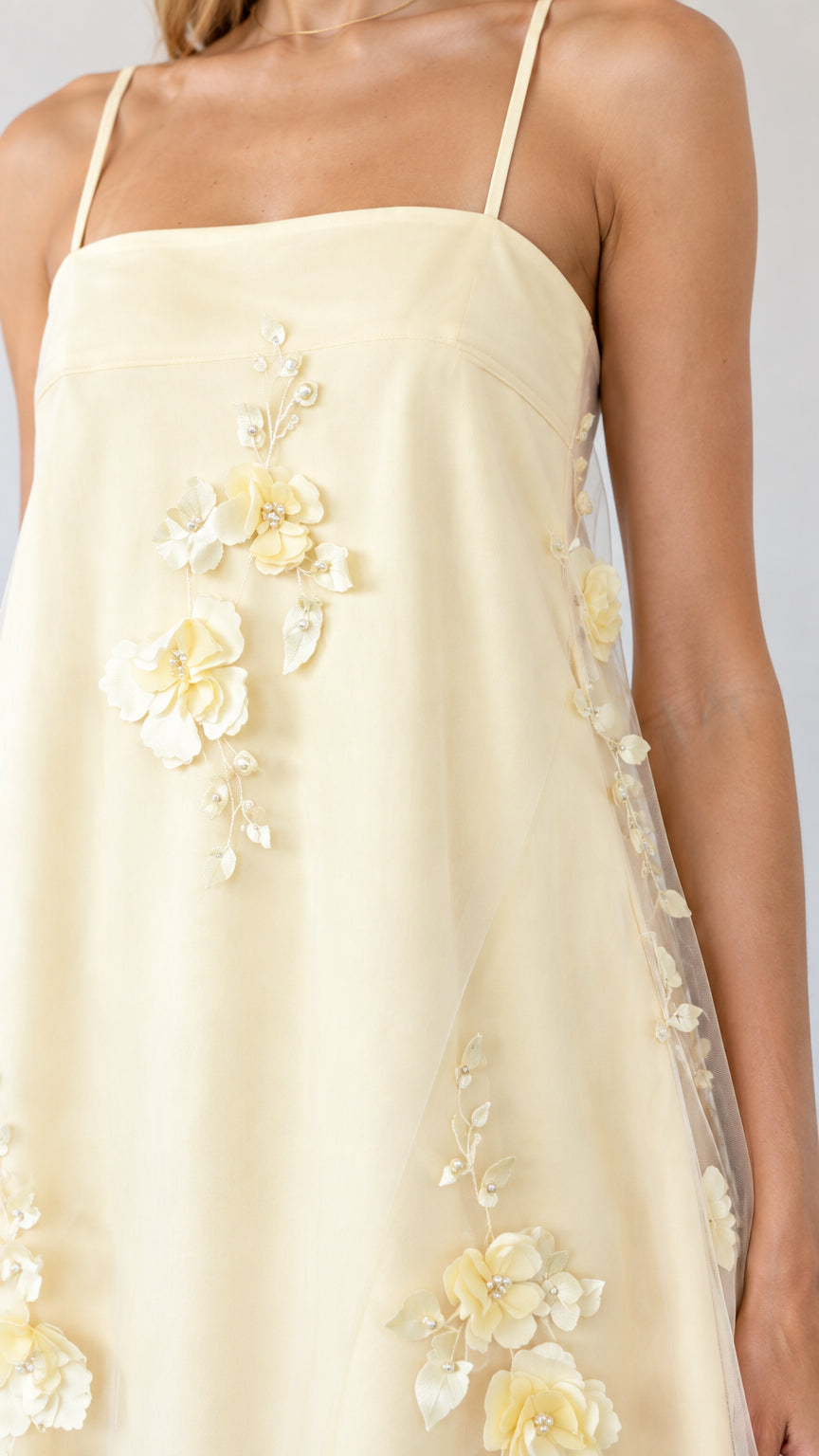 Close-up of dimensional 3D floral appliques on butter yellow tulle fabric