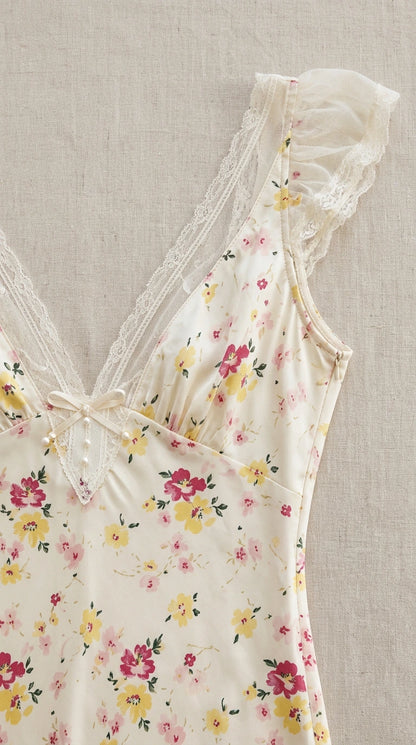 Close-up detail of lace V-neckline, bow, and floral print on cream dress