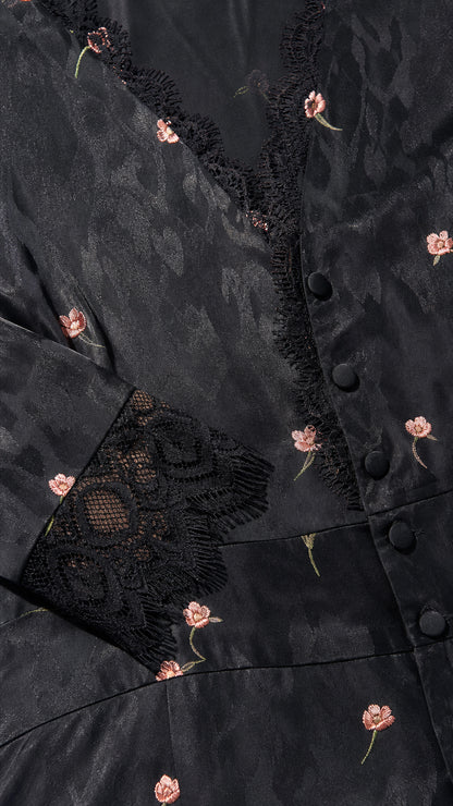 Close-up detail of black floral jacquard fabric, buttons, and lace trim