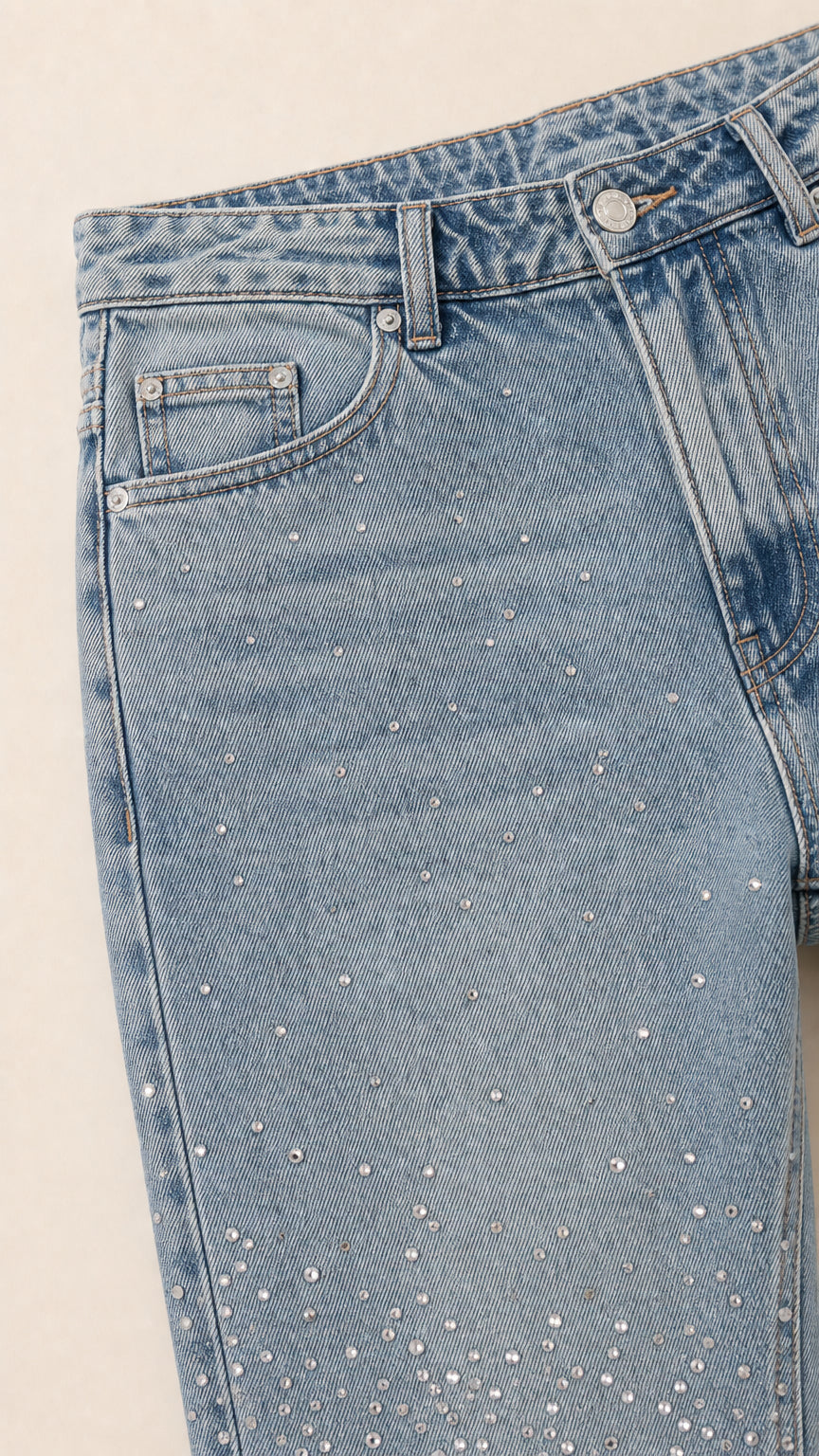 Close up detail of rhinestone crystal embellishments on light blue denim fabric and pocket