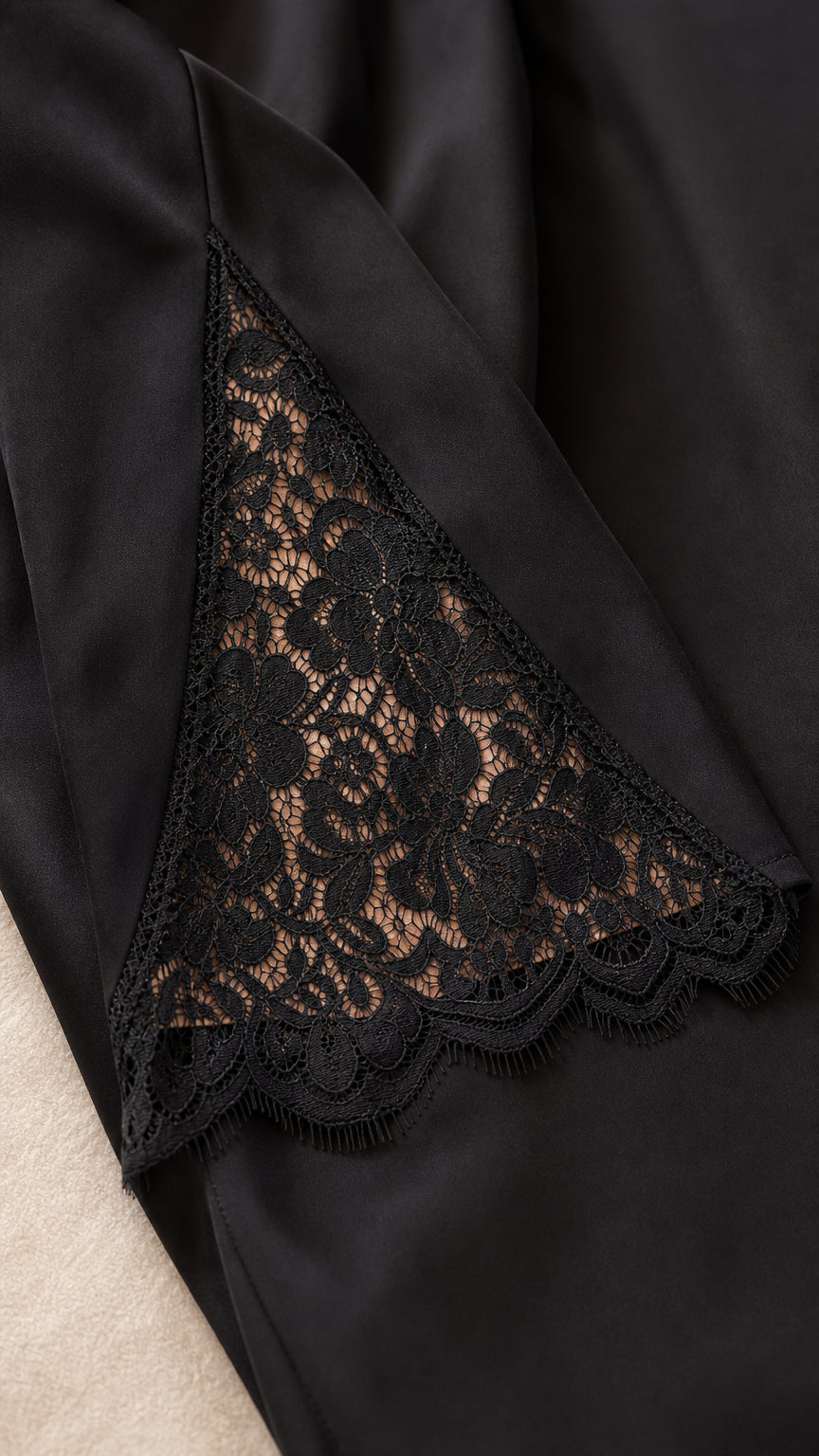 Close-up detail of sheer black floral lace insert on dress sleeve
