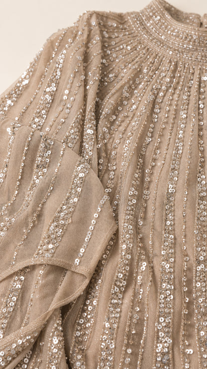 Close-up detail of champagne pleated mesh fabric with linear sequin stripes