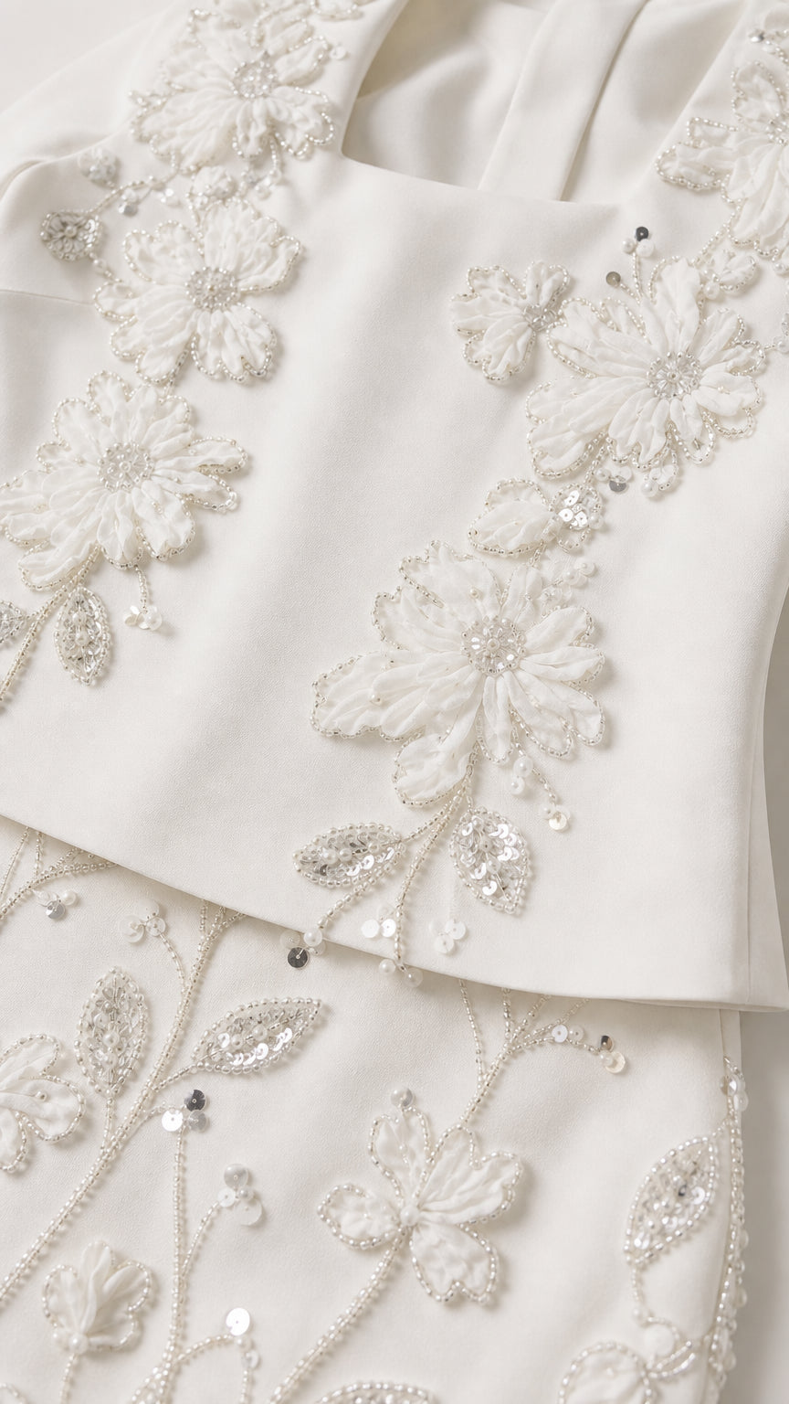 Close-up detail of delicate floral sequin embroidery on white evening fabric