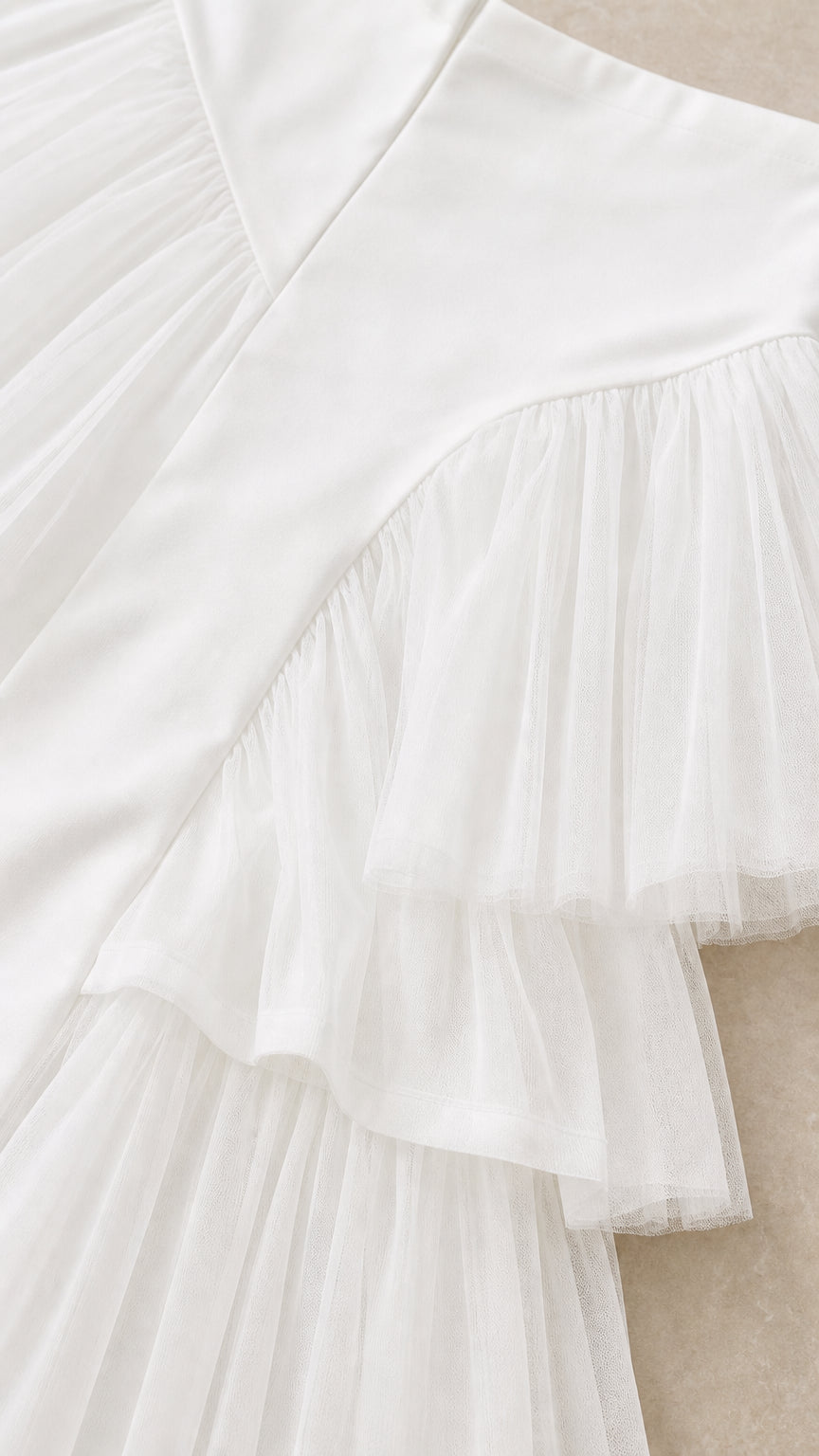 Close-up detail of white smooth woven fabric and pleated tulle ruffle layers