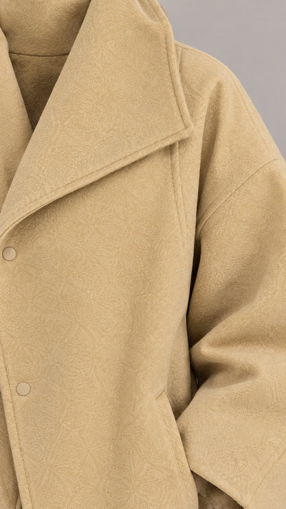 Close-up detail of textured camel wool-touch fabric and snap closure collar