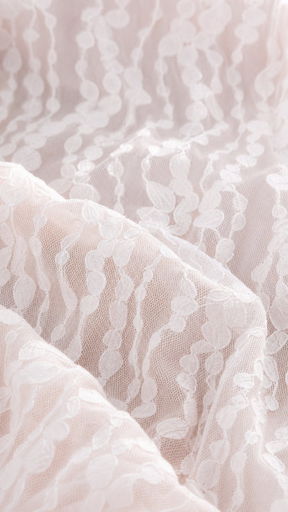 Close-up detail of the delicate patterned lace fabric overlay