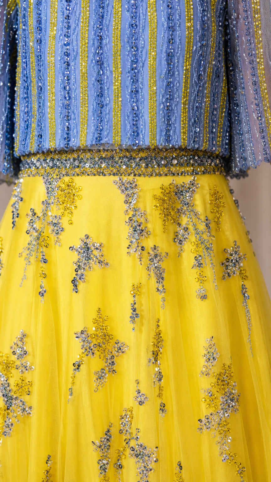 Close-up detail of blue striped beading and yellow floral embroidered tulle fabric
