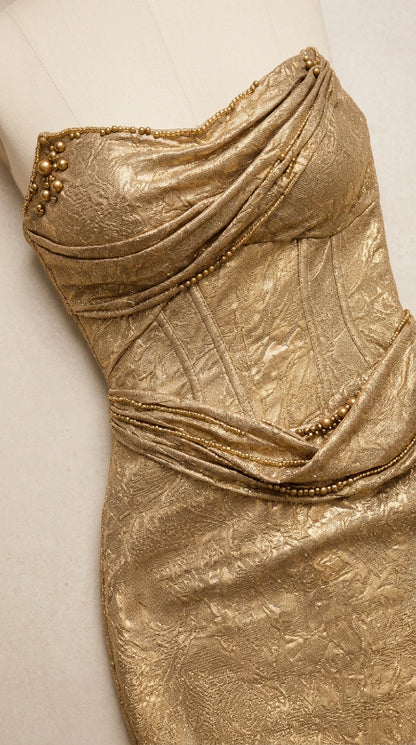 Close-up detail of gold metallic draped bodice with beaded trim and corset seaming