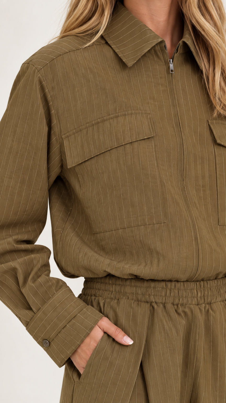 Close-up detail of olive green jumpsuit showing turn-down collar, chest pocket, and elastic waist