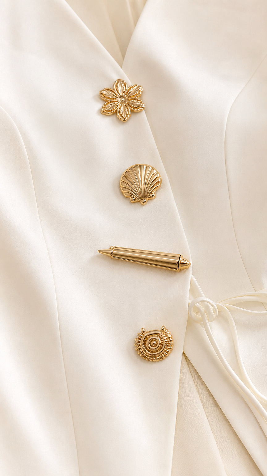 Close-up detail of ornate sculpted gold novelty buttons on the ivory tailored jacket top