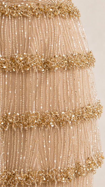 Close-up detail of tiered sequin and bead fringe embellishments on champagne gown