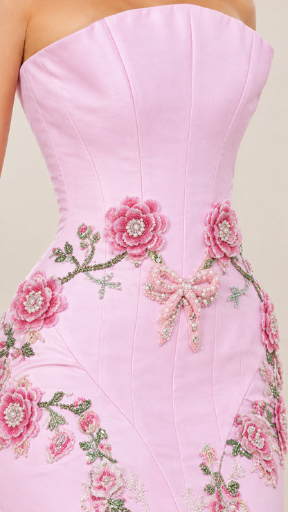 Close-up detail of 3D floral appliqués, embroidery, and bow accent on pink dress bodice