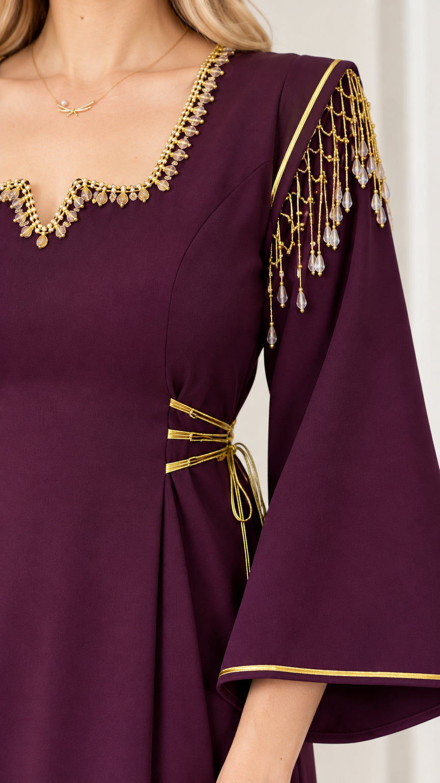 Close-up of golden beaded neckline, shoulder tassel fringe, and waist tie accents