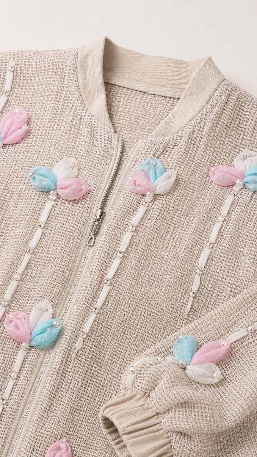 Close-up detail of textured knit fabric, silver zipper, and 3D pastel flower bead embellishments
