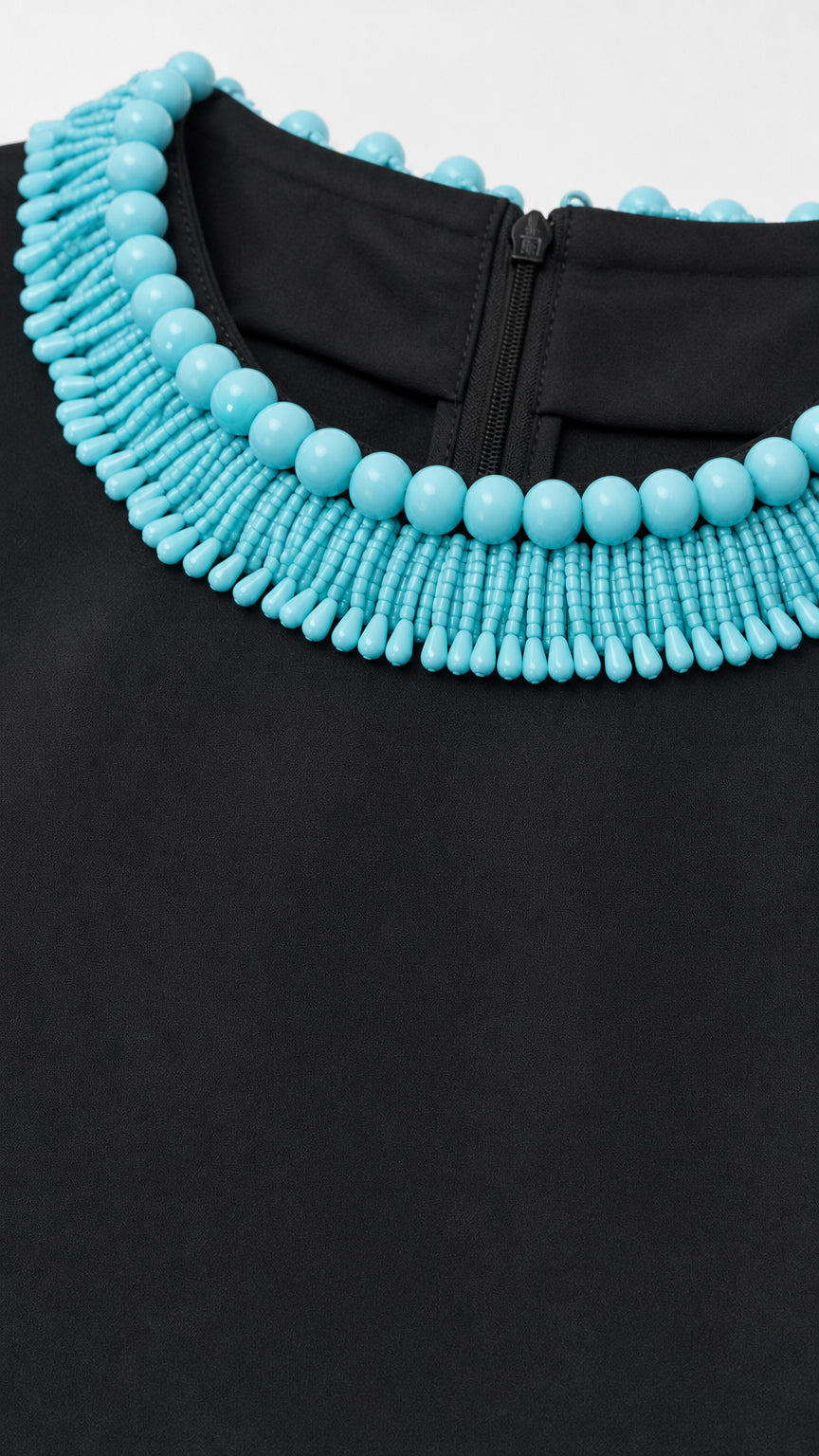 Close-up of turquoise beaded neckline trim on black fabric