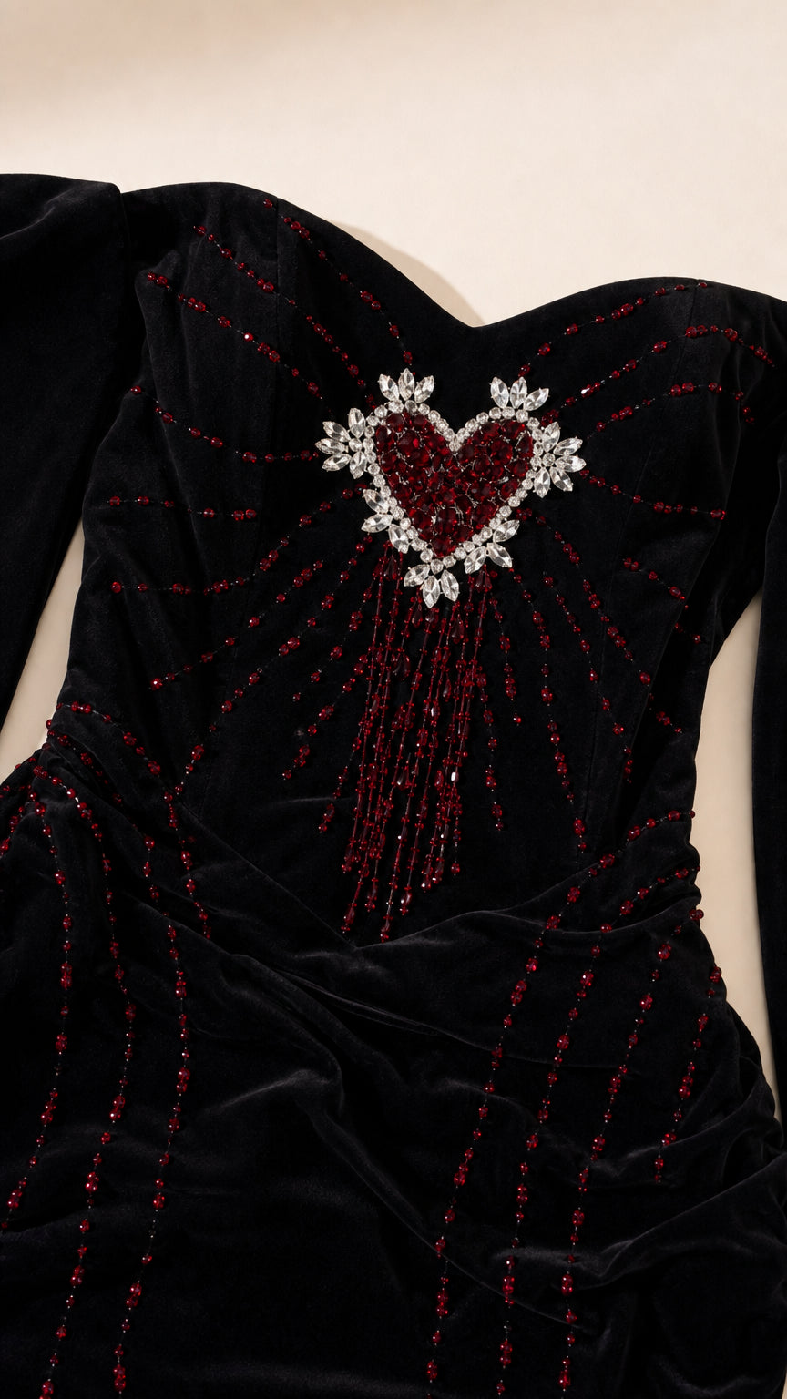 Close-up detail of crystal-beaded heart embellishment on black velvet bodice
