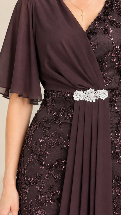 Close-up detail of bodice showing rhinestone waist brooch, chiffon drape, and sequin lace
