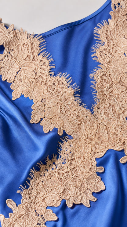 Close-up detail of royal blue satin fabric and intricate beige lace applique