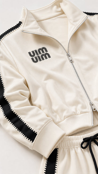 Close-up detail of Cream track jacket collar, zip closure, ribbed cuffs, and embroidered logo
