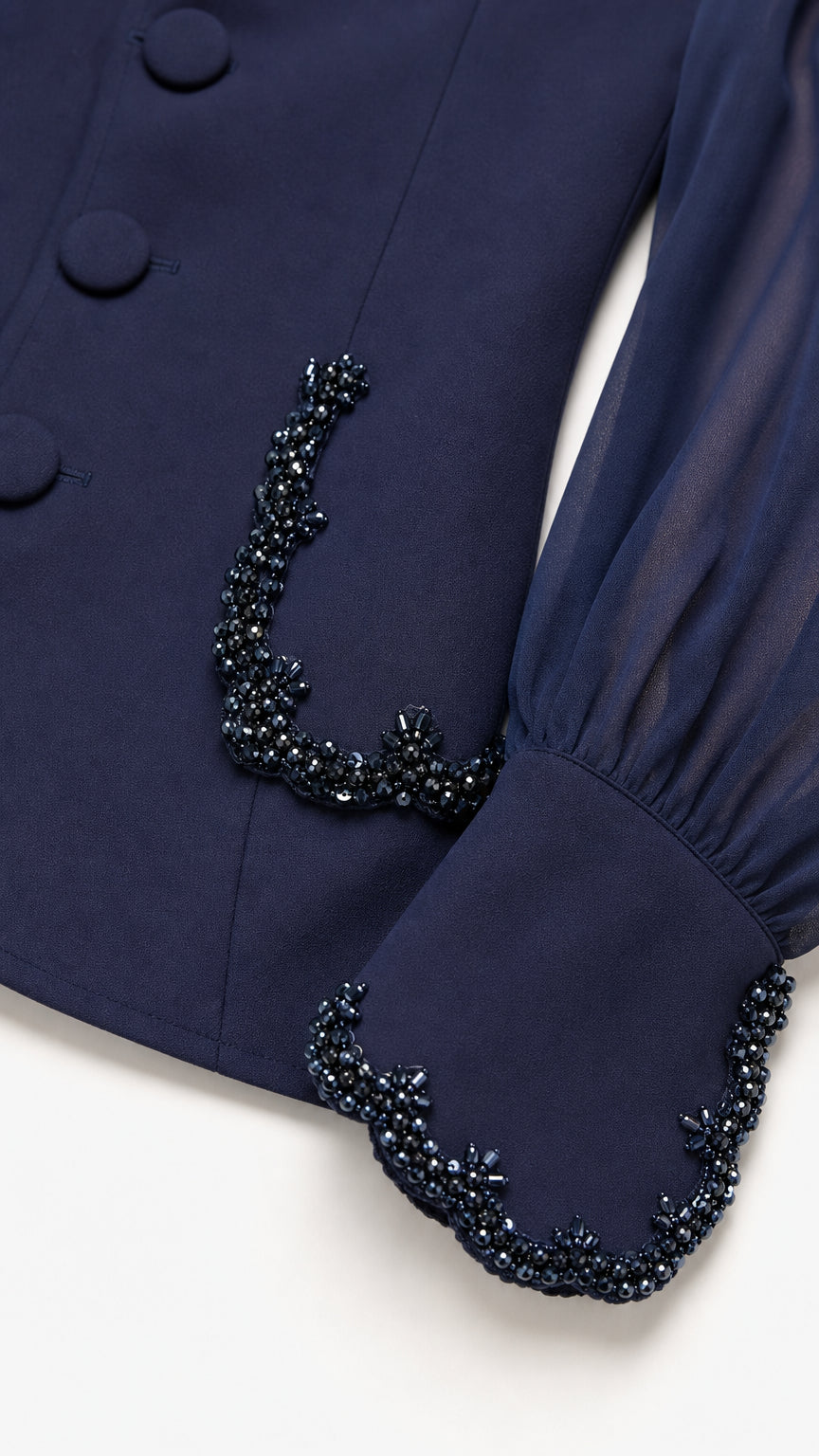 Close-up detail of Navy Blue blazer fabric, covered buttons, sheer sleeve, and intricate beaded cuff trim