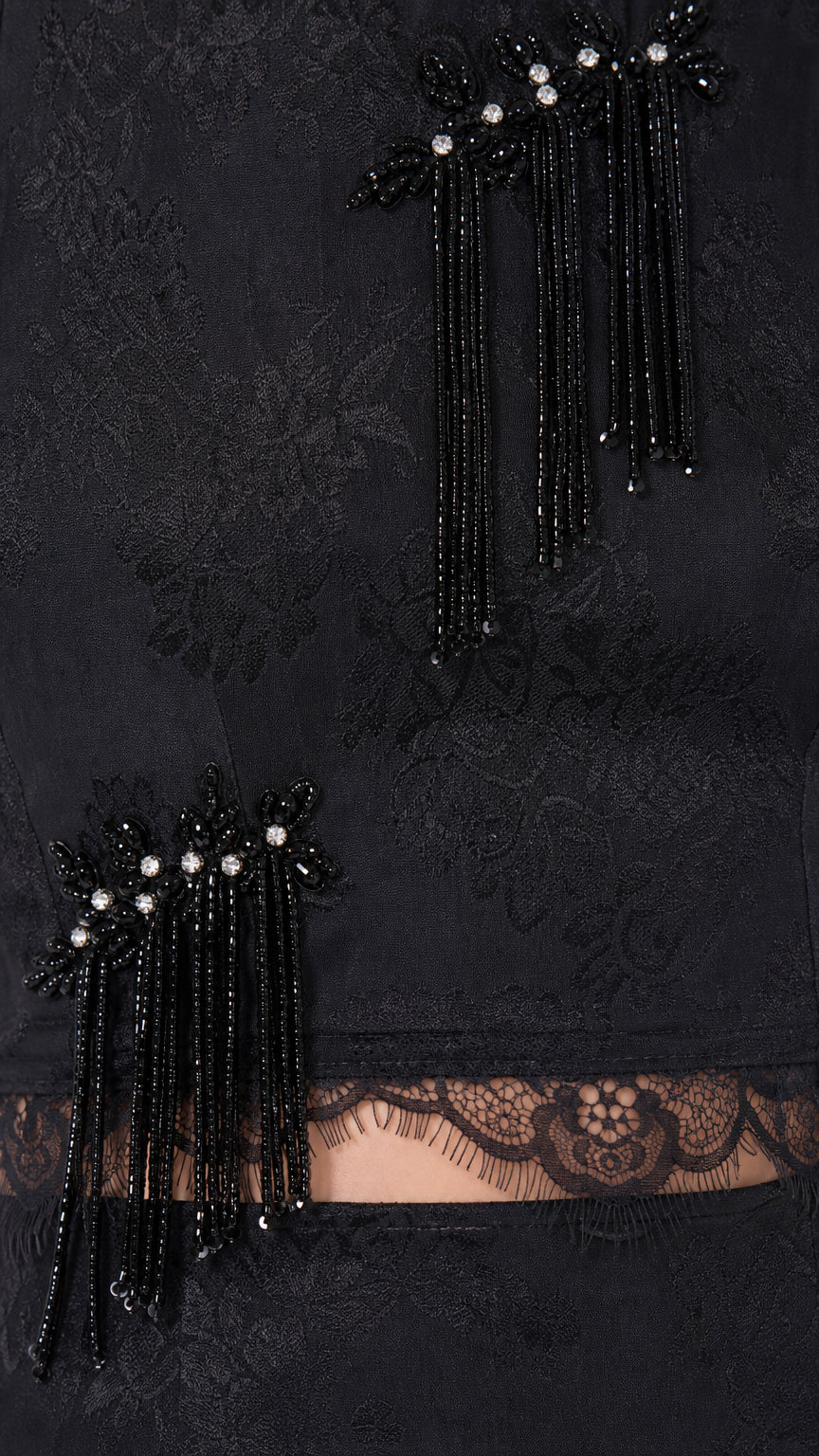 Close-up detail of black beaded fringe tassel appliqué and scalloped lace waist trim