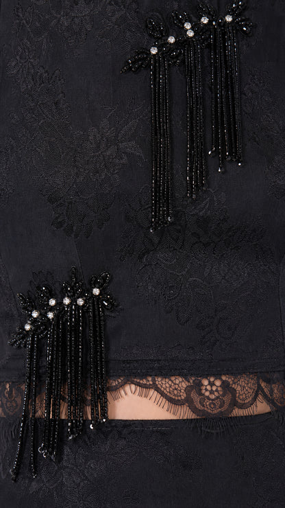 Close-up detail of black beaded fringe tassel appliqué and scalloped lace waist trim