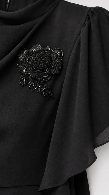 Close-up of black beaded floral applique on draped shoulder of gown