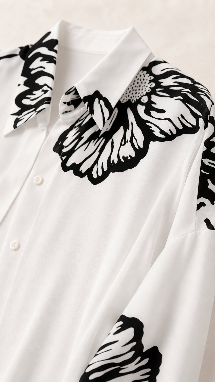 Close-up detail of collar and black graphic floral print on white button-down duster